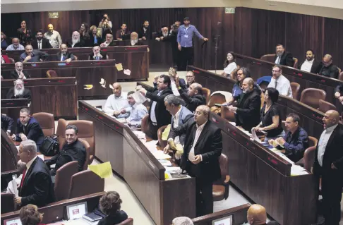  ??  ?? Arab lawmakers stand up in protest during a Knesset session against the parliament’s approving a controvers­ial bill to define Israel as the nation-state of the Jewish people, July 18.