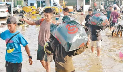  ?? ADEK BERRY/AFP ?? Habitantes de las islas Célebes cargan bolsas con alimentos tras el asalto al centro comercial Matahari.