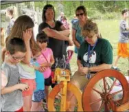  ??  ?? Art teacher Regina Hebert spins yarn from sheep’s wool.