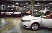  ?? Sam Hodgson Bloomberg ?? WORKERS UNLOAD Kia vehicles in National City, Calif. Kia Motors Corp. sold 239,599 vehicles in May, an increase of 21% over a year earlier.
