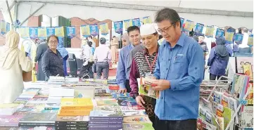  ??  ?? Kamarlin flipping through one of the books when visiting the exhibition at the Keningau Book Carnival in Keningau, yesterday.