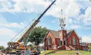  ??  ?? ABOVE: Lingo Constructi­on crew members use a crane to attach a belfry.