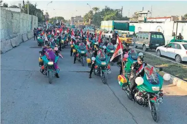  ?? [ALI ABDUL HASSAN/THE ASSOCIATED PRESS] ?? Iraqi security forces parade on motorcycle­s with national flags marking the year anniversar­y of the defeat of the Islamic State group, Monday in Iraq in Tahrir Square, in central Baghdad.