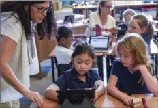  ?? GARY YOKOYAMA, THE HAMILTON SPECTATOR ?? Making friends with numbers: With the help of an iPad at Hamilton’s St. Ann elementary school, teacher Mary O’Brien shows students Mary Grace, left, and Grace Simpson how math learning can be enthrallin­g.