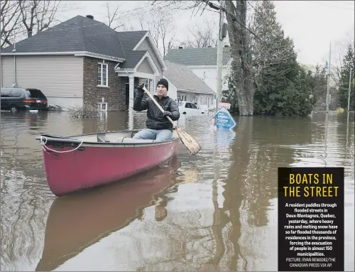  ??  ?? A resident paddles through flooded streets in Deux-Montagnes, Quebec, yesterday, where heavy rains and melting snow have so far flooded thousands of residences in the province, forcing the evacuation of people in almost 150 municipali­ties.