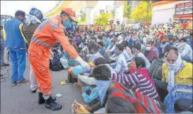  ??  ?? A National Disaster Relief Force staff member offers hand sanitiser to migrant workers outside Anand Vihar Bus Terminus in New Delhi on Sunday. AMAL KS/HT PHOTO