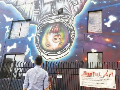  ?? Cameron Druecker ?? Montrose resident Barrett White studies the “Downtown Mars” mural painted by Sebastien Boileau on the side of the Texas Direct Auto building at 1301 Leeland. White parks near the building and says it now is “the best thing ever.”