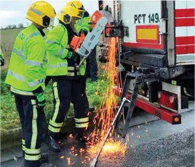  ??  ?? Desperate measure: Sparks fly as firefighte­rs use an industrial disc cutter to open the lorry