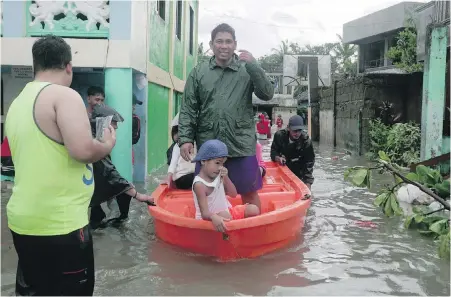  ?? PHOTOS BY THE ASSOCIATED PRESS ?? Villagers in Sorsogon province, northeaste­rn Philippine­s, are helped to escape their flooded homes by boat on Friday after the region was hit by Typhoon Vongfong.