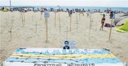  ??  ?? BARCELONA: People sunbathe close to crosses and photograph­s of a dead migrants and refugees, and a banner reading “Invisible frontiers” on Barcelona’s Bogatell beach, during an action called by pro human rights organizati­ons “Tanquem els CIE” (Let’s...