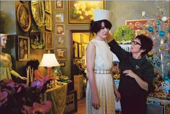  ?? Photog raphs by Katie Falkenberg Los Angeles Times ?? WANDA SOILEAU, right, owner of the vintage store Playclothe­s, adjusts a hat on employee Seera Wright. The shop generates nearly $500,0000 a year in sales, about half from the entertainm­ent industry.