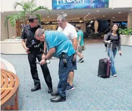  ?? KEVIN SPEAR/STAFF ?? Law-enforcemen­t and airport officials document where a bullet hit after a federal agent accidental­ly shot himself in the foot trying to grab his weapon, which had dislodged.