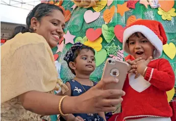  ?? Photos by M. Sajjad, Dhes Handumon, Neeraj Murali and Shihab ?? THE WOW EFFECT... A child reacts to her photo near the wish-tree after attending a Christmas Mass at the St. Michael’s Church in Sharjah. —