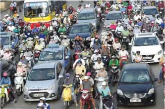  ??  ?? HANOI: Motorcycli­sts ride alongside cars and buses at rush hour on a street in downtown Hanoi yesterday.—AFP