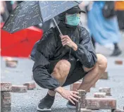  ?? AFP ?? A protester places bricks that were dug up from a nearby pavement onto a road during a rally against a new national security law in Hong Kong on the 23rd anniversar­y of the city’s handover from Britain to China on Wednesday.