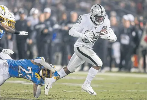  ??  ?? The Raiders’ Josh Jacobs, right, evades a tackle to score the winning touchdown against the Chargers.