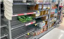  ??  ?? Some supermarke­t shelves have emptied as people stockpile and panic buy.