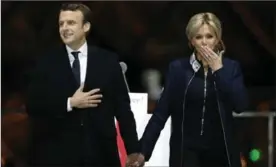  ?? THIBAULT CAMUS, THE ASSOCIATED PRESS ?? French president-elect Emmanuel Macron holds hands with his wife, Brigitte, during a victory celebratio­n outside the Louvre museum in Paris on Sunday.