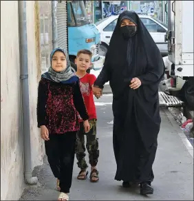  ?? (AP/Vahid Salemi) ?? Husseini and her children walk April 21 in a poor suburb of Tehran.