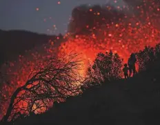  ?? Reuters ?? A woman climbs a hill with a child to see the Cumbre Vieja volcano as it continues to erupt in Tacande de Arriba on the Canary Island of La Palma, Spain.