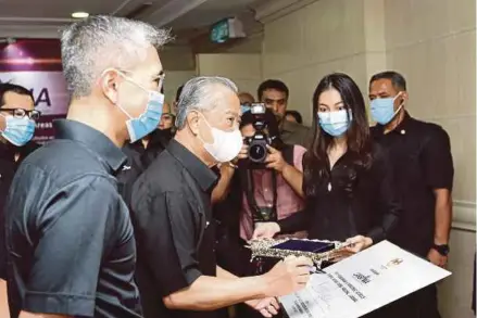  ?? (Foto Mohd Fadli Hamzah /BH) ?? Muhyiddin menandatan­gani plak ketika mengadakan lawatan ke unit LAKSANA dan pelancaran Papan Pemuka Digital sambil diperhatik­an Tengku Zafrul di Putrajaya, semalam.