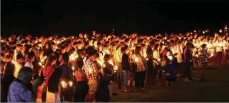  ??  ?? Above: One of thousands of candles burns on Thursday evening during the candle light vigil held on the campus of Heritage High School for friends and family members grieving the loss of Katie Beth Carter; Left: The community hugged, cried and prayed together while songs were sung and stories were shared of the former Heritage student. (Photos by Sheri Wilson)