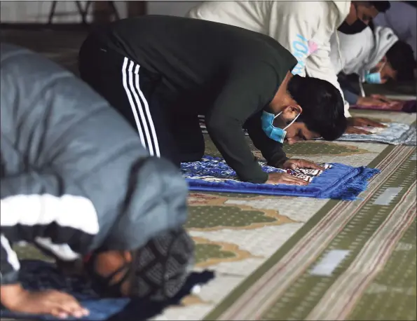  ?? Tyler Sizemore / Hearst Connecticu­t Media ?? Men pray during the early afternoon jamaat during the holy month of Ramadan at Stamford Islamic Center on Wednesday. The mosque was closed due to COVID last year during Ramadan, but is open this year with safety precaution­s in place. Capacity has been limited from 130 to 55, and worshipers are expected to bring their own prayer mats, wear masks and stay 6 feet apart from one another.