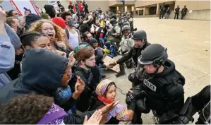  ?? COLIN MULVANY/THE SPOKESMAN-REVIEW VIA AP ?? BANGUN EMPATI: Para polisi ikut berlutut di hadapan para demonstran di Spoken, Washington, Amerika Serikat, Minggu (31/5). Aksi berlutut itu dilakukan para demonstran sebagai simbol duka terhadap kematian George Floyd pada 25 Mei.