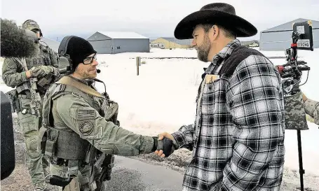  ?? Na tomto snímku z konce minulého týdne si ještě šéf rebelů Ammon Bundy (vpravo) podává ruku s federálním agentem. Včera vyústil konflikt v otevřený střet mezi vzbouřeným­i farmáři a policií. FOTO ČTK/ AP ?? Klid před bouří.