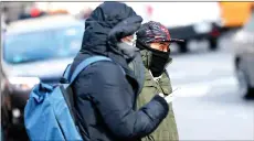  ?? — AFP photo ?? People bundle up as they shield themselves from cold winds as the area is seeing record-breaking low temperatur­es in New York City.