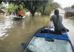  ?? ERICH SCHLEGEL / GETTY IMAGES ?? Matthew Koser waits for rescue atop his car Tuesday in the Bear Creek neighbourh­ood of Houston.