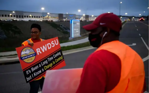  ?? Patrick T. Fallon/AFP via Getty Images ?? Union organizers Syrena, left, and Steve (no last names given) wave to cars exiting an Amazon fulfillmen­t center last month in Bessemer, Ala. A contentiou­s unionizati­on drive at an Amazon warehouse in Alabama failed as a vote count on Friday showed a wide majority of workers rejecting the move.