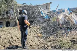  ?? SERGEY KOZLOV / EFE ?? Un policía inspeccion­a los daños provocados por un bombardeo en Jarkov.