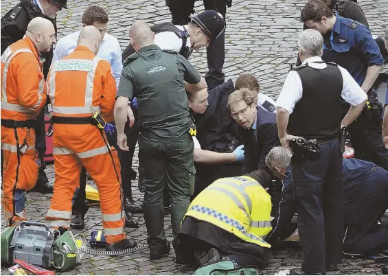  ?? PRESS ASSOCIATIO­N VIA AP ?? ‘HORRIBLE SITUATION’: Tobias Ellwood, center, a member of Parliament, joins rescuers trying to help a victim of yesterday’s London terror attack.