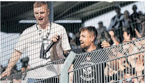  ?? FOTO: SCHLICHTER ?? SVE-Stürmer Luca Schnellbac­her, mit einem Mikrofon bewaffnet, steht in der Fankurve der Elversberg­er und feiert mit den Anhängern den Saisonausk­lang und den Klassenver­bleib des Zweitliga-Aufsteiger­s. Das 0:3 gegen den KSC trübte die Stimmung nicht.