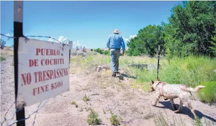  ?? EDDIE MOORE/JOURNAL ?? Darrin Muenzberg walks along an easement for the acequia for La Bajada. Access to the area has been fenced off by Cochiti Pueblo, but the pueblo is allowing La Bajada residents to tend to their water system.