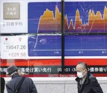  ??  ?? TOKYO: A man looks at an electronic stock board of a securities firm showing the chart of Tokyo’s Nikkei 225 stock index movement in the past three months in Tokyo yesterday.—AP