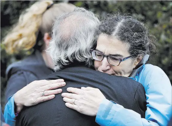  ?? Keith Srakocic The Associated Press ?? People embrace along the street Saturday in the Squirrel Hill neighborho­od of Pittsburgh where a shooter opened fire during services at the Tree of Life synagogue.