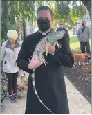  ?? SUBMITTED PHOTO ?? Rev. Matthew Tralies, parochial administra­tor at St. Francis of Assisi Parish in Springfiel­d, holds the winner of the Most Exotic Pet category at Sunday’s Blessing of the Animals event at St. Francis of Assisi Church, held in celebratio­n of the St. Francis of Assisi Feast Day. “Ray” the iguana is owned by Grant Derhofer.