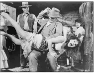  ??  ?? In this infamous movie publicity shot, John Wayne spanks Maureen O’ Hare in “McLintock!” Patrick Wayne, John’s son, is on the left.