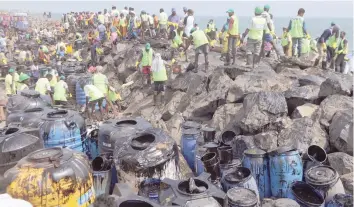  ?? — AFP ?? Firefighte­rs and volunteers try to clean up oil that has washed ashore in Chennai on Saturday, after an oil tanker and an LPG tanker collided off Kamarajar Port in Ennore.