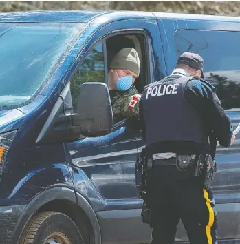  ?? ANDREW VAUGHAN / THE CANADIAN PRESS ?? A soldier talks with an RCMP officer at a checkpoint on Thursday in Portapique, N.S., as the military brought in personnel, modular tents, lights, tables, chairs and generators to locations in the province to help the investigat­ion.