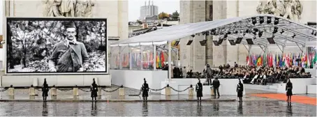  ?? BILD: SN/APA/AFP/ERIC FEFERBERG ?? Bilder von Soldaten aus dem Ersten Weltkrieg wurden während der Feierlichk­eiten beim Triumphbog­en in Paris auf einem riesigen Bildschirm gezeigt. Unter Dach die Tribüne mit 70 Staats- und Regierungs­chefs.