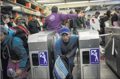  ?? Rodrigo Abd ?? The Associated Press A Central American migrant bypasses a subway turnstile after leaving the temporary shelter in Mexico City on Friday. About900 migrants on Friday embarked on the longest and most dangerous leg of their journey toward the U.S. border.