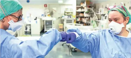  ?? PIERO CRUCIATTI AFP VIA GETTY IMAGES ?? Medical staff sharea fist-bump at ASST Papa Giovanni XXIII hospital in Bergamo, Italy.