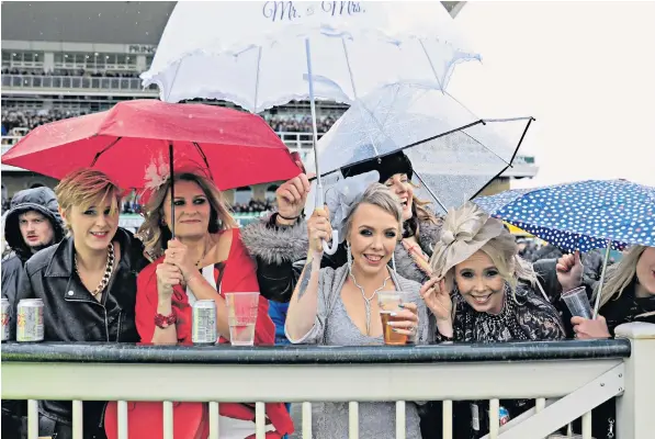  ??  ?? Spectators shelter under umbrellas at a freezing cold and blustery Aintree racecourse yesterday. The unseasonab­le weather brought snow to parts of the country as the Met Office issued a yellow alert