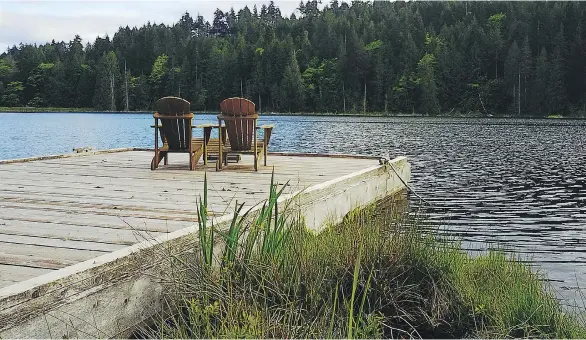  ??  ?? A pair of Adirondack chairs awaits visitors and owners on the dock on Bullock Lake at the Cottages on Salt Spring Island. Paddleboar­ds and canoes are also available for the more active.