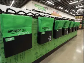  ?? TED S. WARREN — THE ASSOCIATED PRESS ?? Amazon-branded reusable shopping bags await customers inside the Amazon Go Grocery store in Seattle.