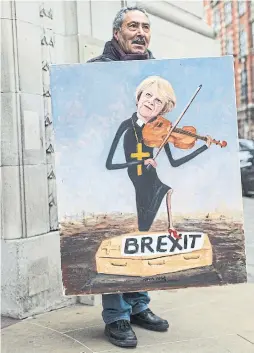  ?? JACK TAYLOR GETTY IMAGES ?? Political artist Kaya Mar stands with a painting he created depicting U.K. Prime Minister Theresa May.