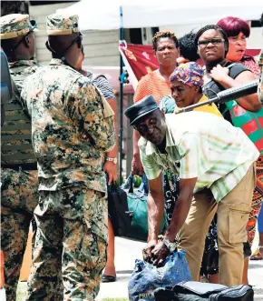  ?? FILE ?? Soldiers search passengers’ bags after a Coaster bus was stopped at a checkpoint at Industrial Terrace, Kingston, on September 24, 2018. Francis Wade argues that the only reason the JDF remains relatively unsullied is because it has fewer contact hours with citizens.